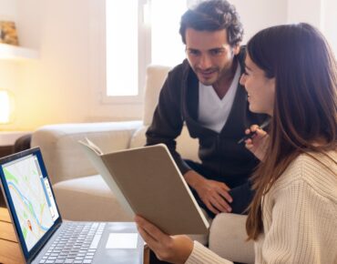 A couple using a laptop with maps to explore real estate automation software for their home search., missed call text back software for real estate, Missed call recovery for real estate agents